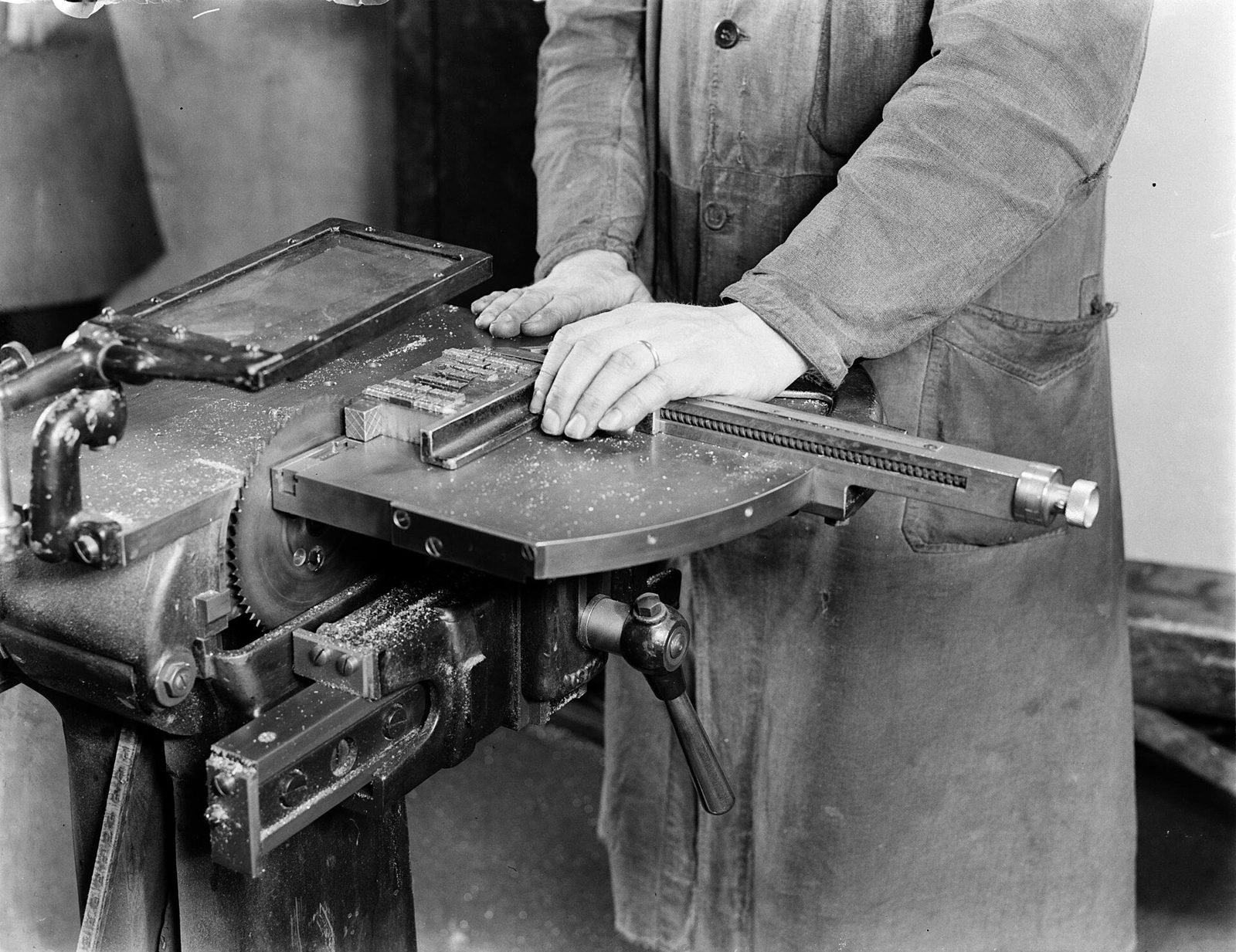 A typesetter cutting lines of machine-set type by hand in 1949