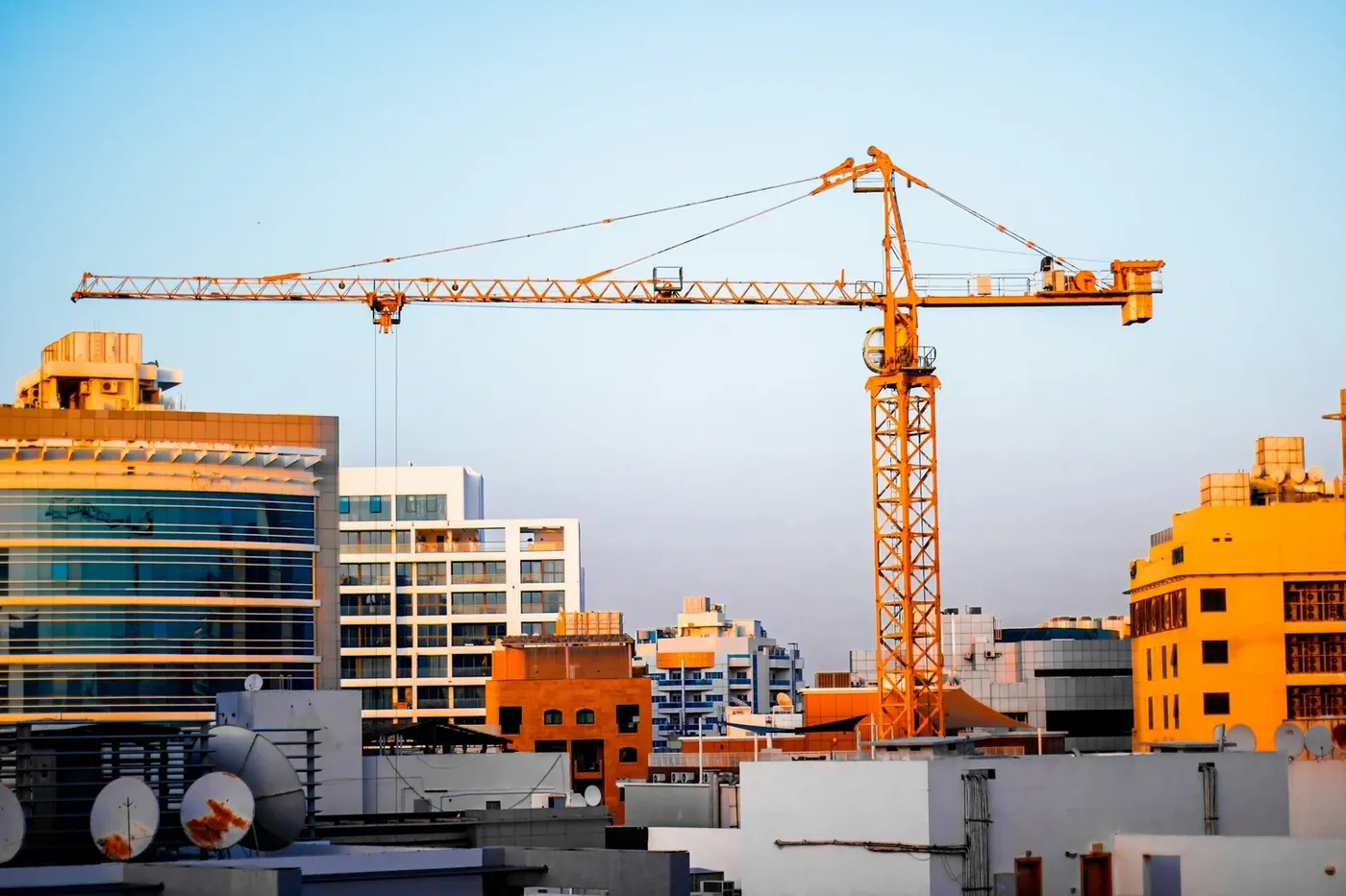A tower crane over new buildings against a blue sky
